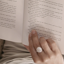 Still from Indian Horse, consisting of a close-up shot of a book and the hand of the reader holding the pages.